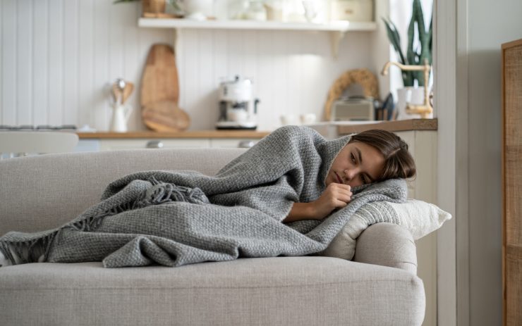 Ragazza che riposa sul divano avvolta da un plaid