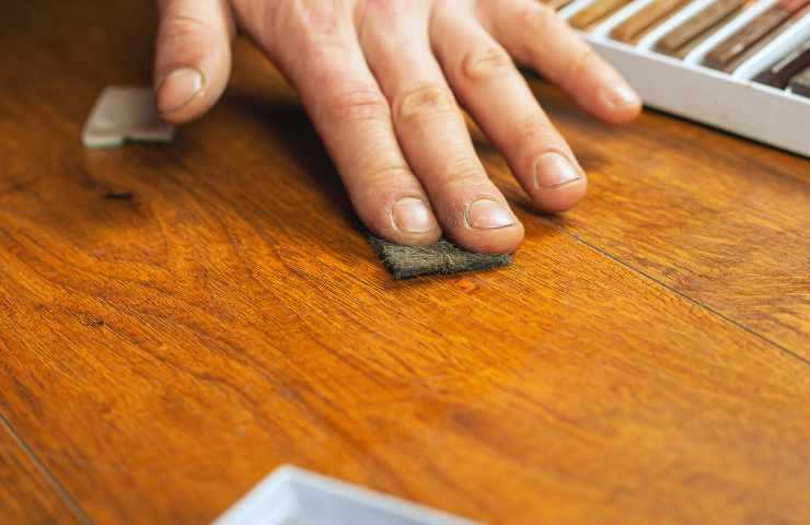 uomo tocca parquet con la mano
