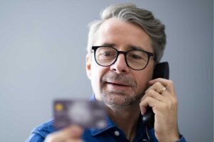 uomo al telefono con bancomat in mano