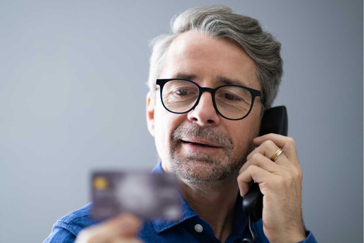 uomo al telefono con bancomat in mano